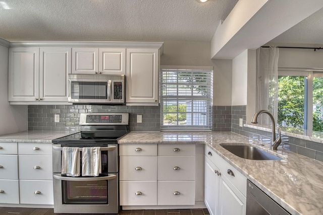 kitchen featuring white cabinetry, sink, stainless steel appliances, and light stone countertops