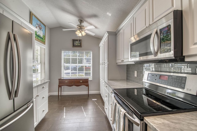 kitchen featuring appliances with stainless steel finishes, backsplash, a textured ceiling, white cabinets, and vaulted ceiling