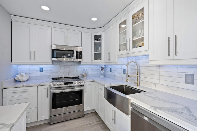 kitchen featuring stainless steel appliances, sink, white cabinets, and light stone counters