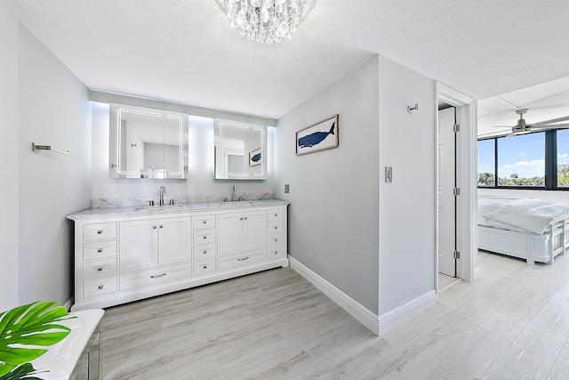 bathroom featuring vanity, hardwood / wood-style flooring, ceiling fan with notable chandelier, and a textured ceiling