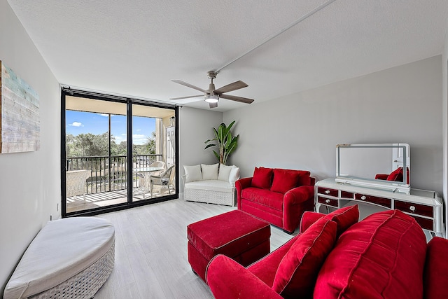 living room featuring ceiling fan, light hardwood / wood-style flooring, floor to ceiling windows, and a textured ceiling