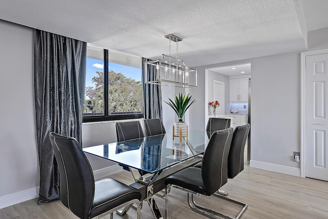 dining area with light hardwood / wood-style floors and a textured ceiling