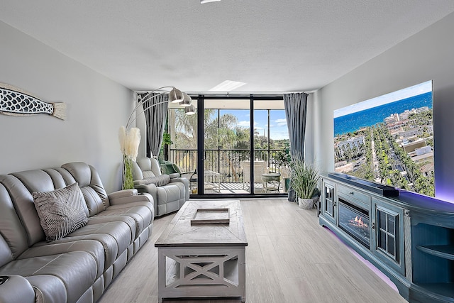 living room featuring floor to ceiling windows, a textured ceiling, and light wood-type flooring