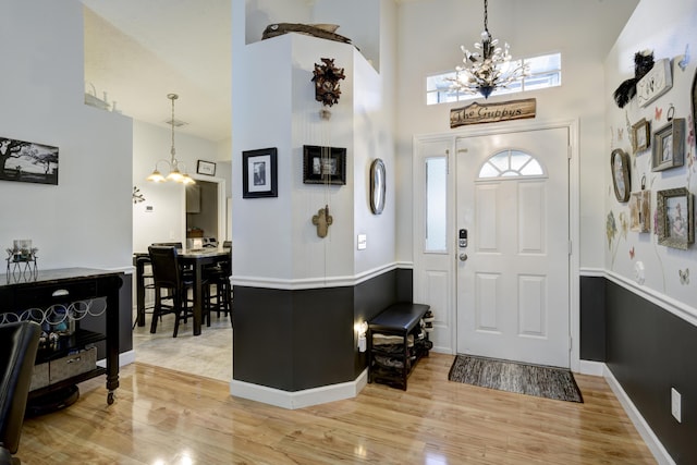 entryway with a towering ceiling, hardwood / wood-style floors, and an inviting chandelier