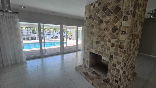 unfurnished living room featuring a brick fireplace and light tile patterned floors