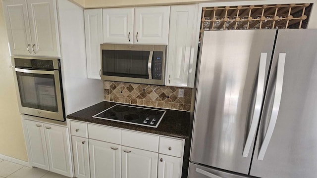 kitchen with tasteful backsplash, light tile patterned floors, white cabinets, and appliances with stainless steel finishes