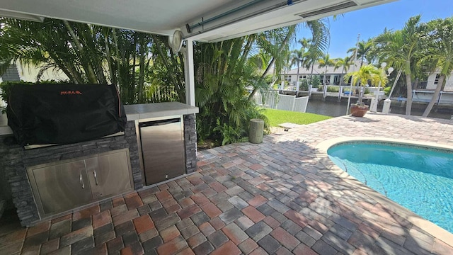 view of pool featuring exterior kitchen, a patio, and grilling area