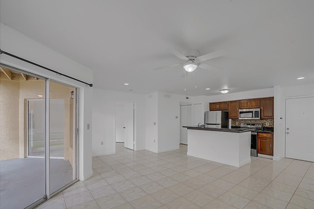 kitchen with light tile patterned flooring, a kitchen island, appliances with stainless steel finishes, backsplash, and ceiling fan