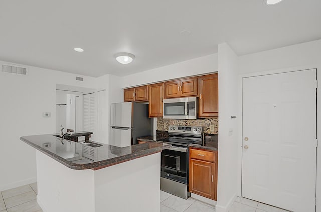 kitchen featuring stainless steel appliances, sink, a center island with sink, and backsplash