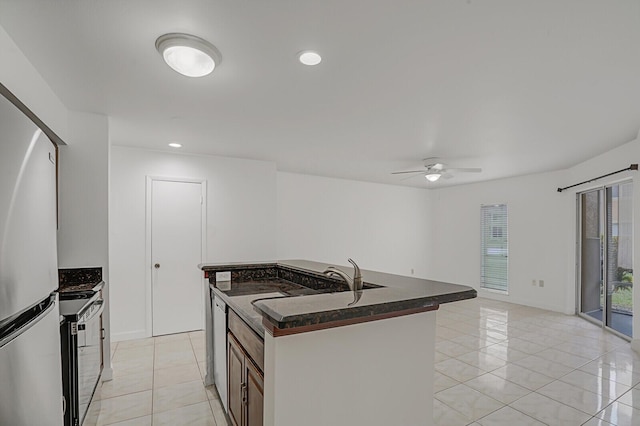 kitchen featuring light tile patterned flooring, electric range oven, stainless steel refrigerator, sink, and a center island with sink