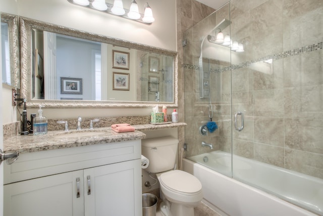 full bathroom with enclosed tub / shower combo, vanity, and toilet