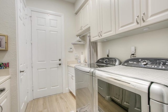 washroom featuring cabinets, separate washer and dryer, and light hardwood / wood-style floors