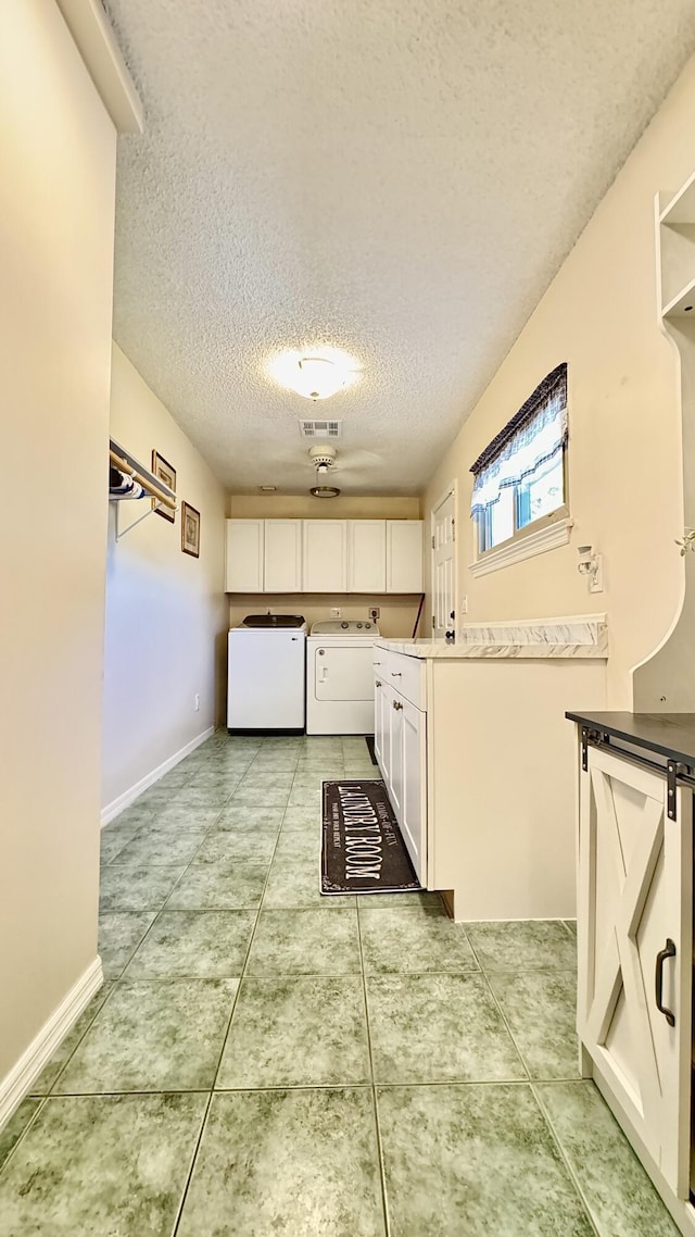 kitchen with light tile patterned floors, a textured ceiling, visible vents, white cabinetry, and washing machine and clothes dryer