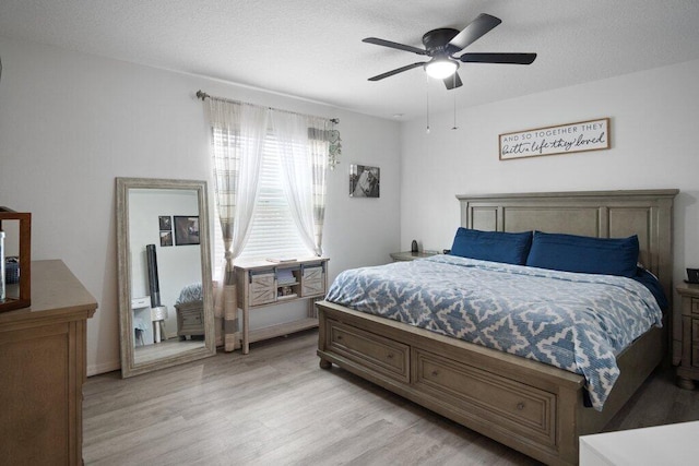 bedroom with a textured ceiling, light hardwood / wood-style floors, and ceiling fan