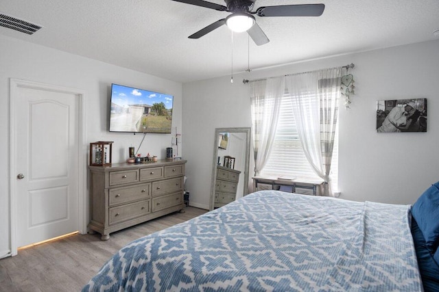 bedroom with ceiling fan, light hardwood / wood-style flooring, and a textured ceiling