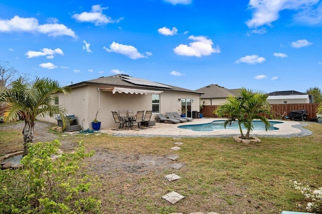 rear view of property with a fenced in pool, a yard, a patio area, and solar panels