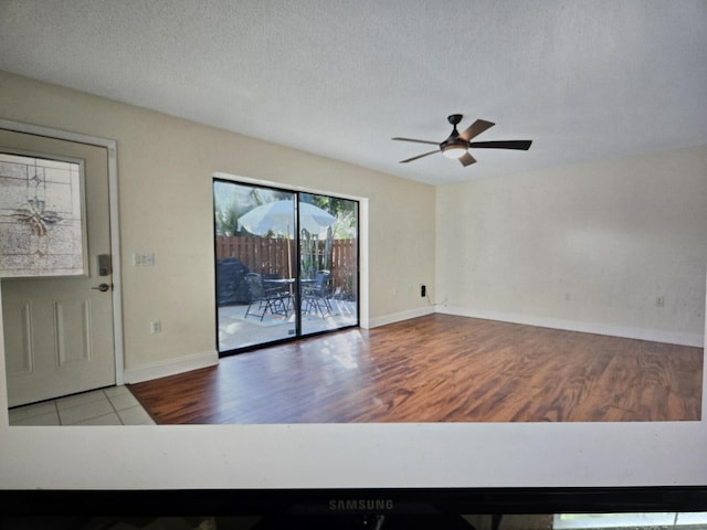 empty room with ceiling fan, a textured ceiling, and light wood-type flooring