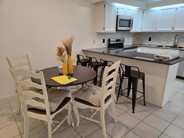 kitchen with appliances with stainless steel finishes, sink, white cabinets, backsplash, and kitchen peninsula