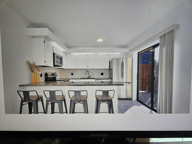 kitchen featuring sink, kitchen peninsula, white cabinets, and appliances with stainless steel finishes