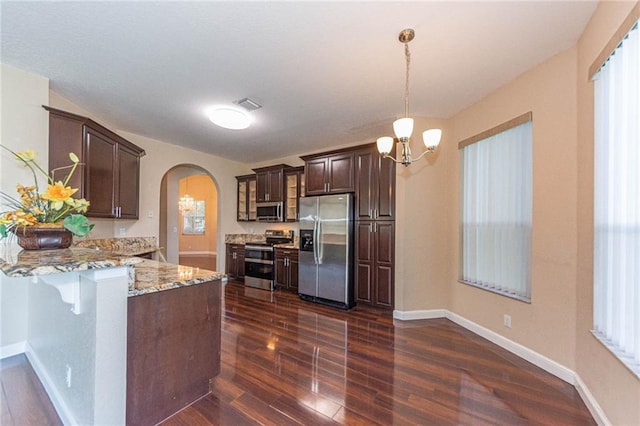 kitchen with pendant lighting, light stone counters, dark wood-type flooring, and appliances with stainless steel finishes