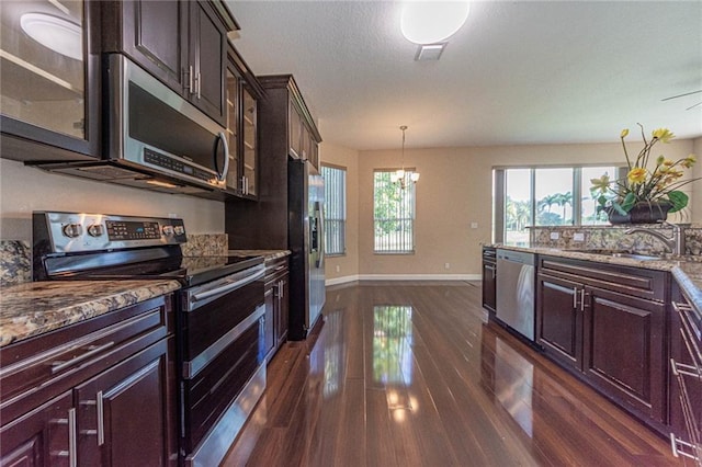 kitchen with pendant lighting, sink, dark hardwood / wood-style flooring, light stone counters, and stainless steel appliances