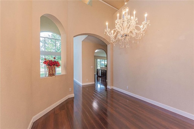 unfurnished room with plenty of natural light, dark hardwood / wood-style floors, and a chandelier