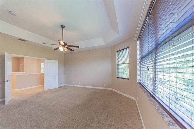 unfurnished bedroom with a raised ceiling, light carpet, and ceiling fan