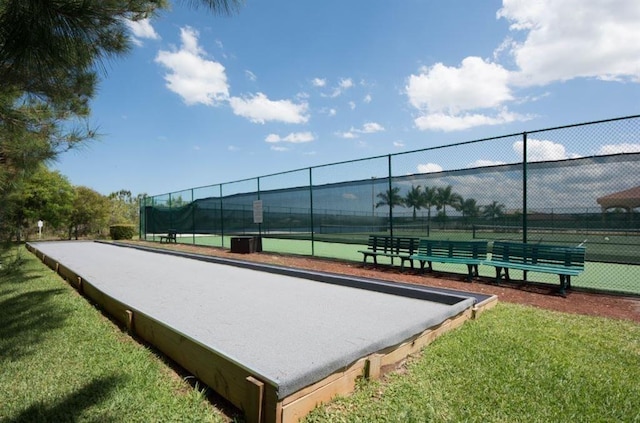 view of property's community featuring a yard and tennis court