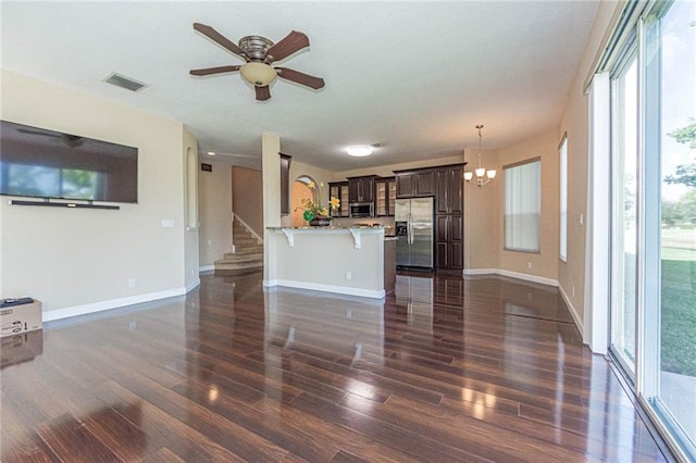 unfurnished living room featuring dark hardwood / wood-style floors and ceiling fan with notable chandelier