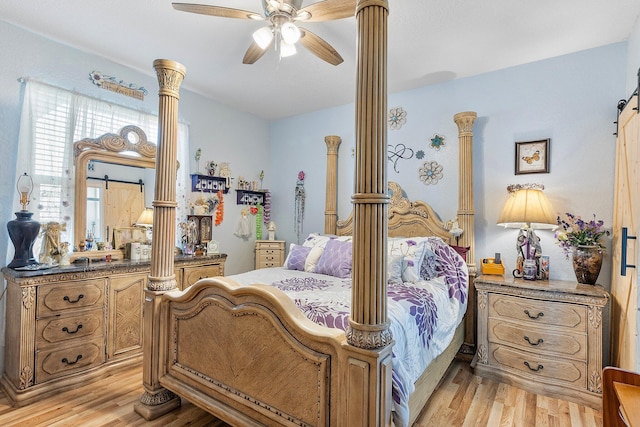 bedroom featuring ceiling fan, a barn door, decorative columns, and light hardwood / wood-style flooring