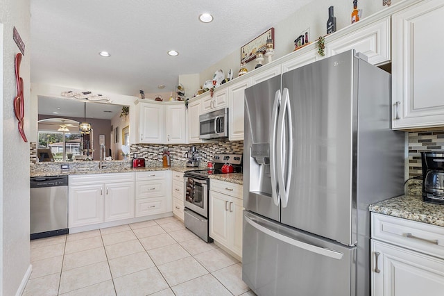 kitchen featuring light stone counters, appliances with stainless steel finishes, and white cabinets