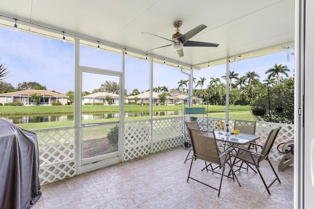 sunroom with a healthy amount of sunlight, ceiling fan, and a water view