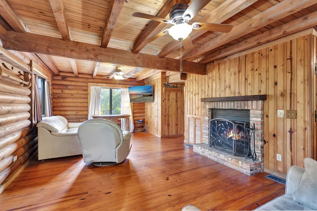 living room featuring wood ceiling, hardwood / wood-style flooring, ceiling fan, beam ceiling, and a fireplace