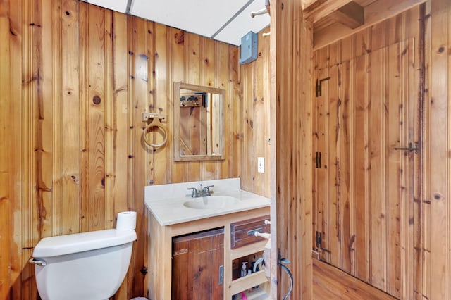 bathroom featuring vanity, toilet, and wood walls