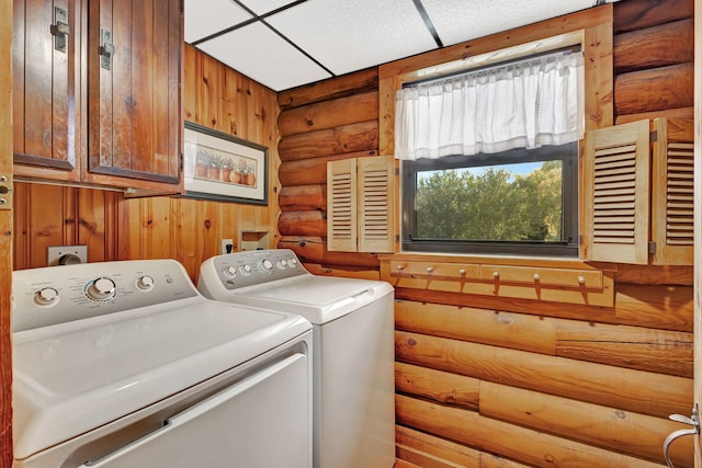 clothes washing area with separate washer and dryer, log walls, and cabinets