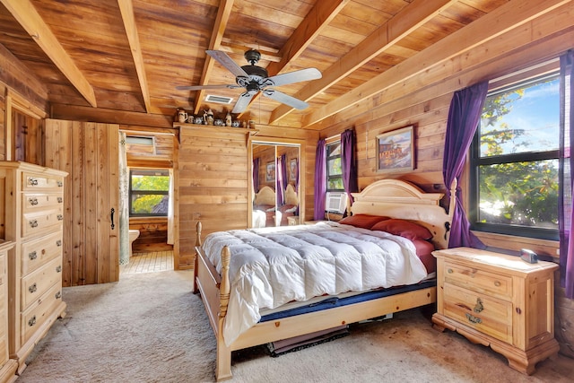 bedroom with ensuite bathroom, wood walls, wood ceiling, light carpet, and beam ceiling