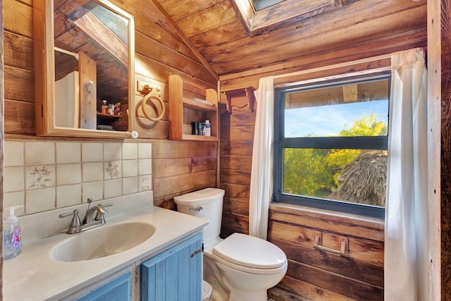 bathroom with lofted ceiling with skylight, wood walls, backsplash, vanity, and toilet