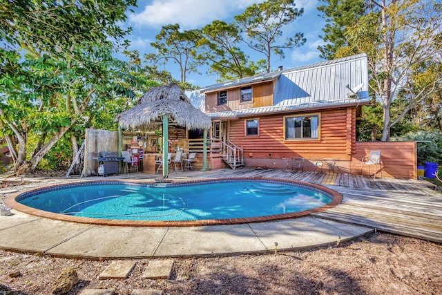 view of swimming pool with grilling area and a deck