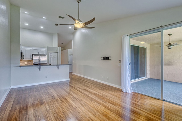 unfurnished living room with ceiling fan, light hardwood / wood-style floors, and a towering ceiling