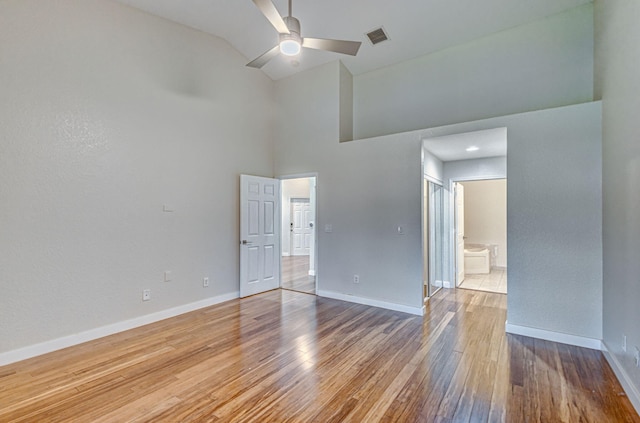 empty room with wood-type flooring, high vaulted ceiling, and ceiling fan