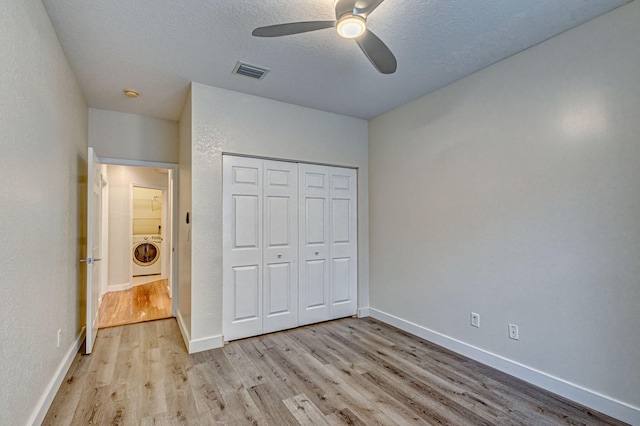 unfurnished bedroom featuring ceiling fan, a textured ceiling, washer / dryer, a closet, and light wood-type flooring