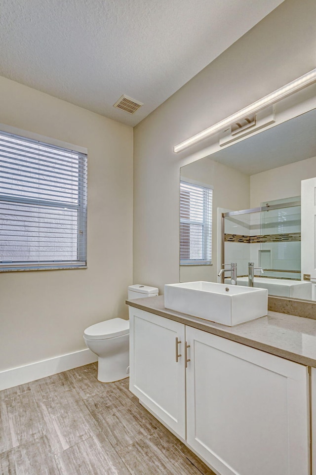 bathroom with vanity, wood-type flooring, a textured ceiling, toilet, and walk in shower