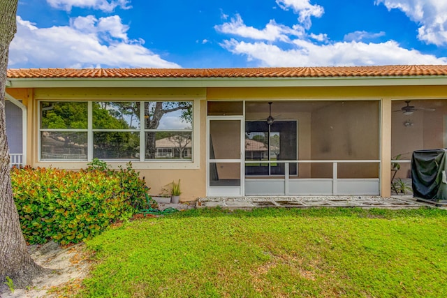 view of side of home featuring a sunroom, ceiling fan, and a lawn