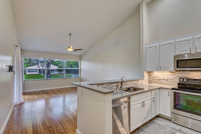 kitchen featuring white cabinetry, lofted ceiling, kitchen peninsula, and appliances with stainless steel finishes