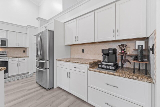 kitchen featuring white cabinetry, sink, dark stone countertops, stainless steel appliances, and crown molding