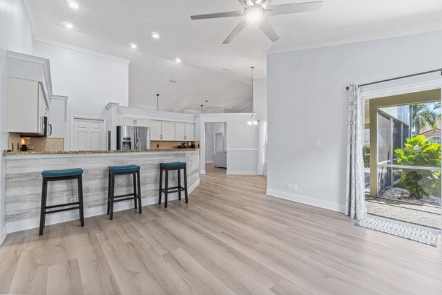 living room with lofted ceiling, light wood-type flooring, ceiling fan, crown molding, and a textured ceiling