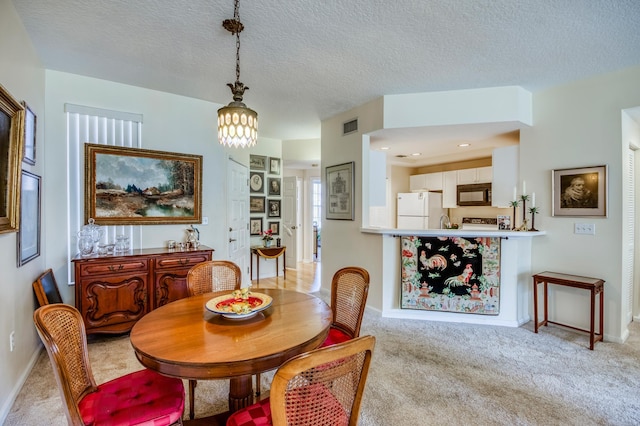 dining space with light carpet and a textured ceiling