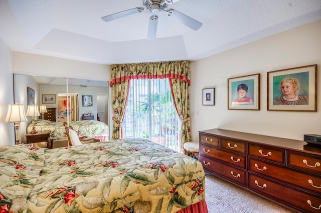 carpeted bedroom featuring a closet, access to outside, a raised ceiling, and ceiling fan