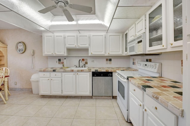 kitchen with white cabinetry, sink, decorative backsplash, light tile patterned floors, and white appliances