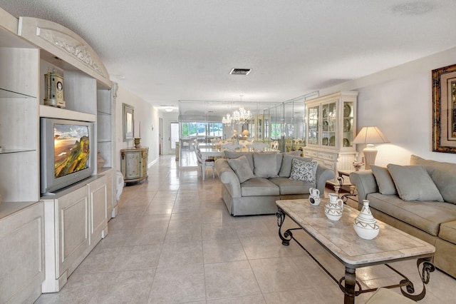 living room with an inviting chandelier, a textured ceiling, and light tile patterned floors